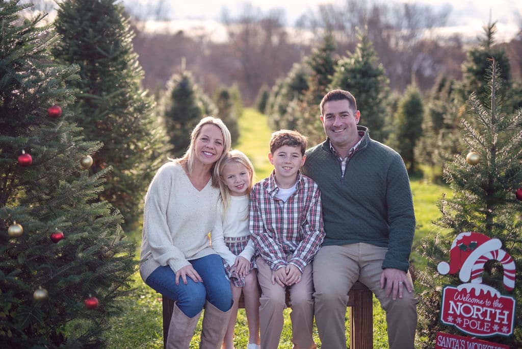 Family sitting together beside a Christmas tree at a holiday mini session