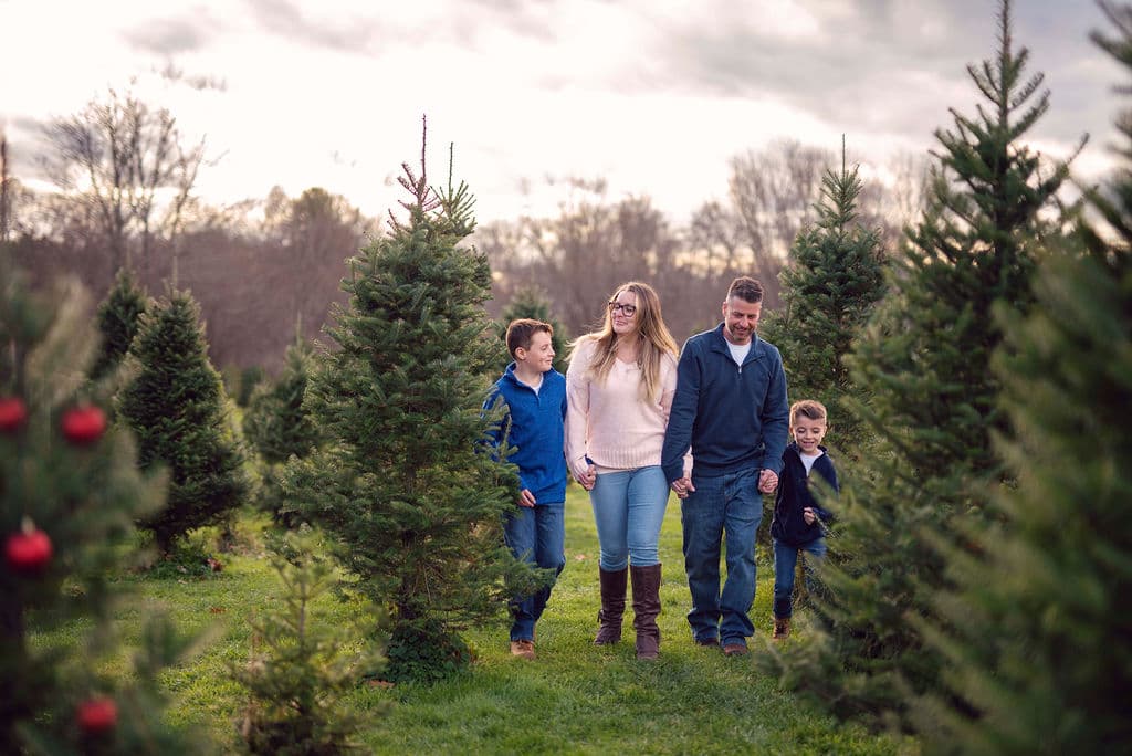 Family of five standing among decorated Christmas trees
