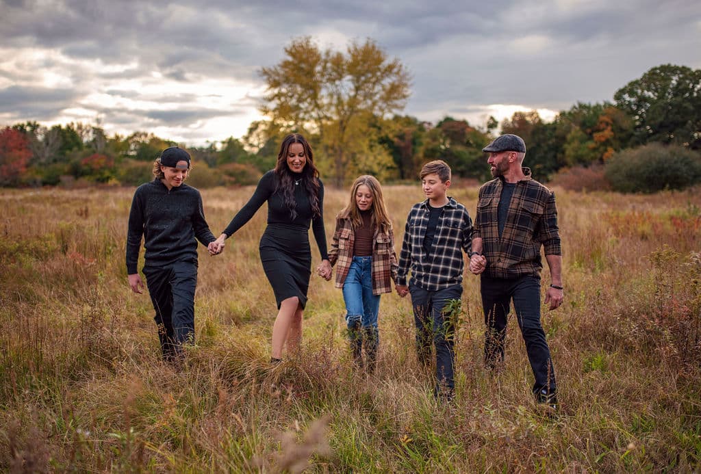 Family walking hand in hand through a fall field