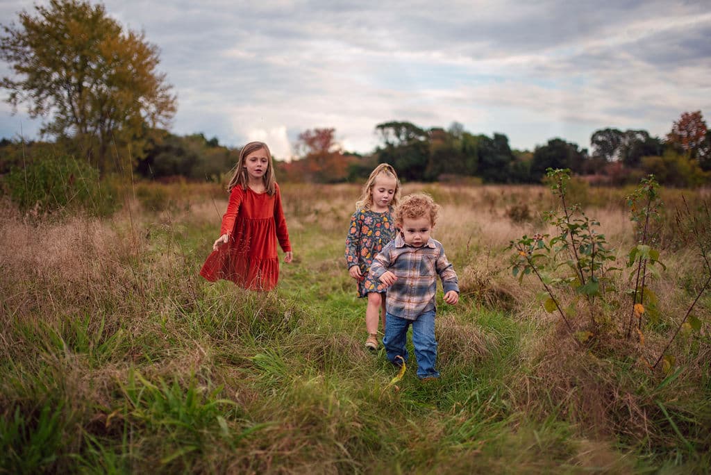 Three young children playing in a fall field
