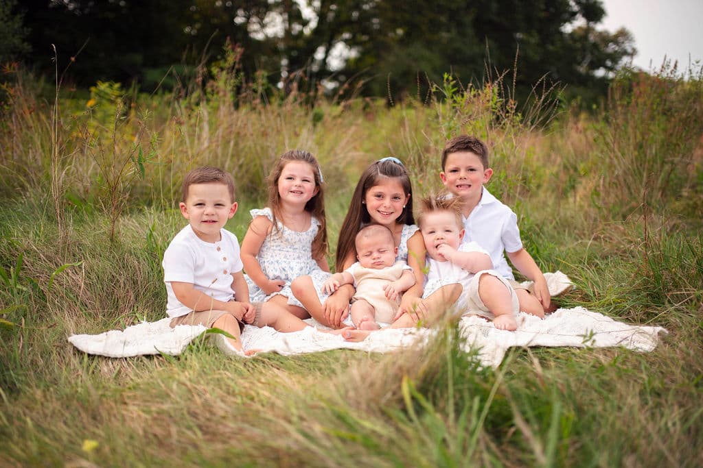Siblings sitting on a blanket in a summer meadow