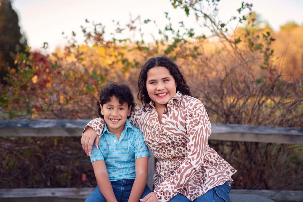 Mother and son smiling together on a bench among fall leaves