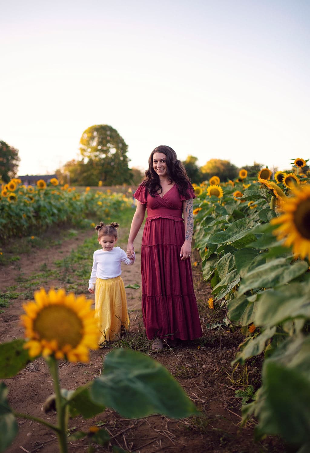 Mother and daughter walking through a sunflower field