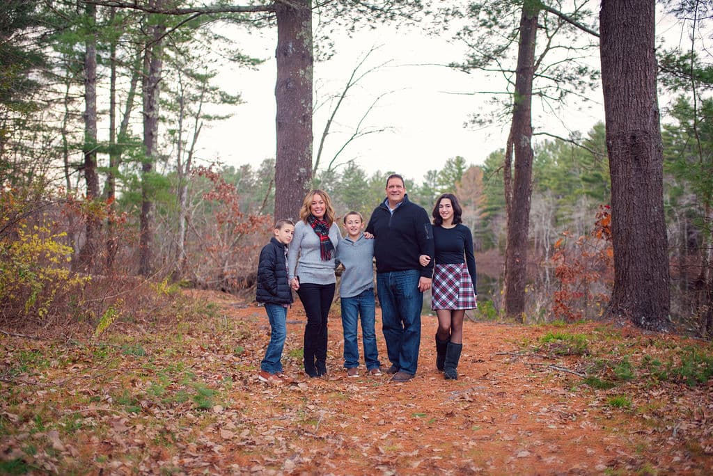 Family standing together on a wooded trail in the fall