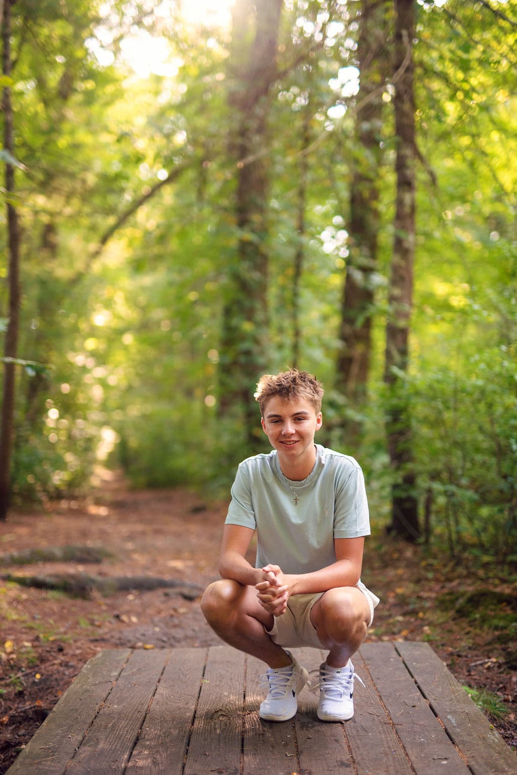 Senior guy on a wooded boardwalk in dappled sunlight