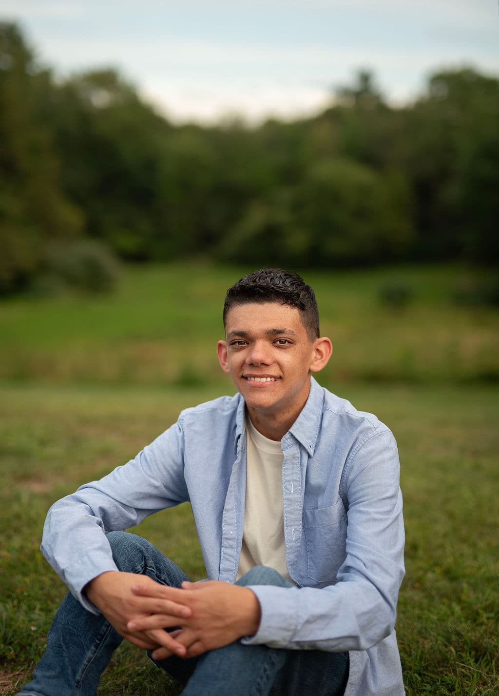 Senior guy in a light blue shirt sitting in a green field